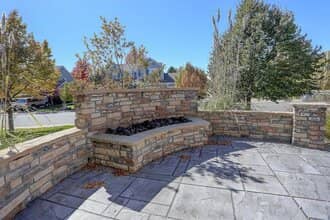 Outdoor stone fireplace with decorative stone wall and patio