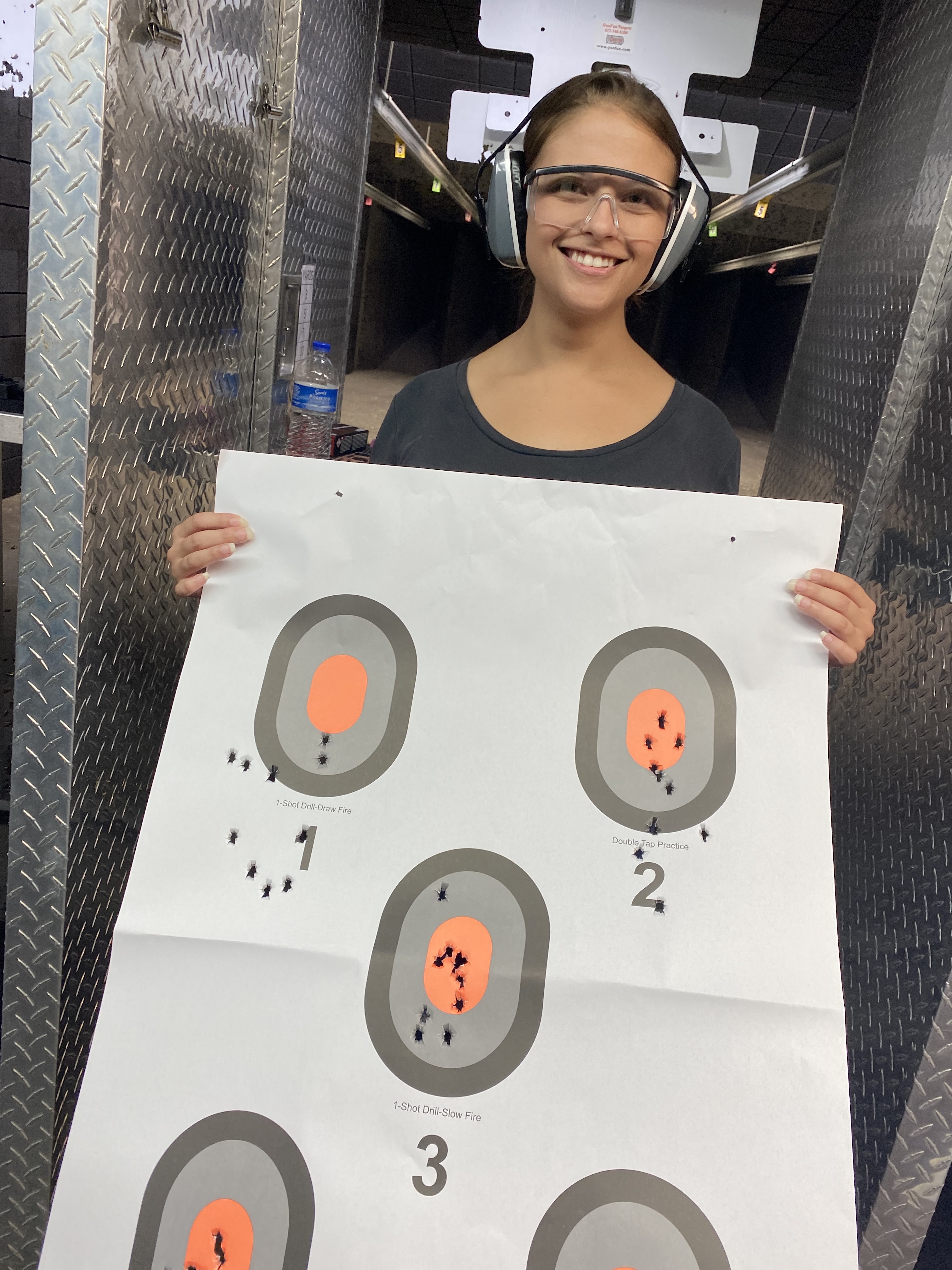 confident woman student holding target after gun class