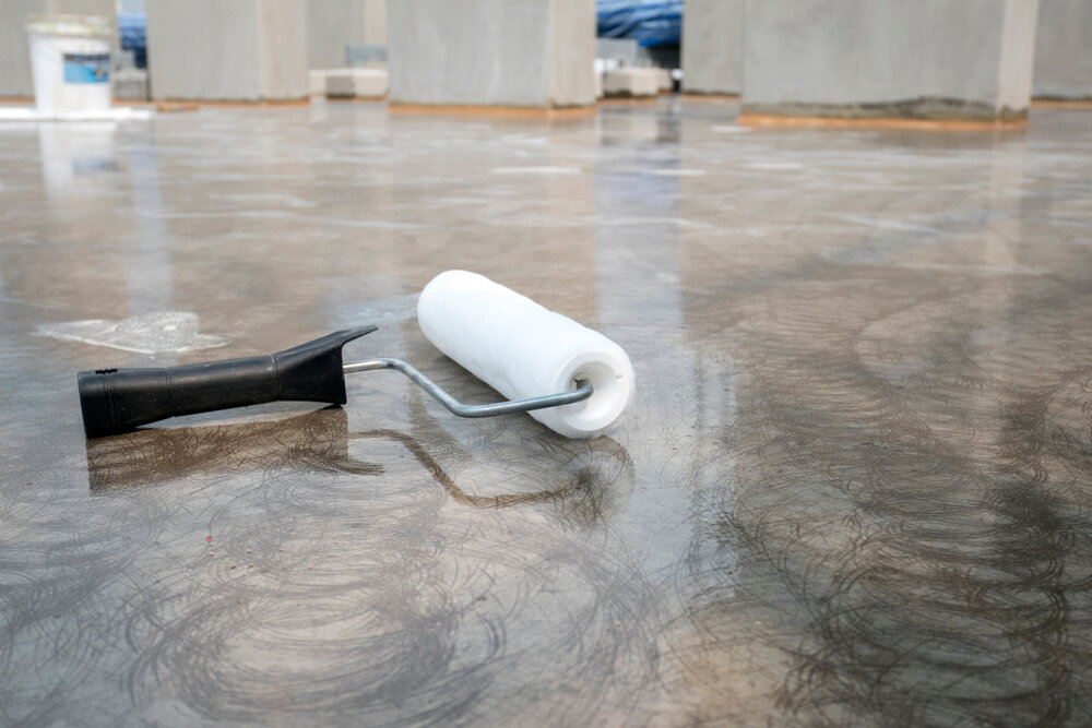 paint roller laying on top of dry epoxy covered cement