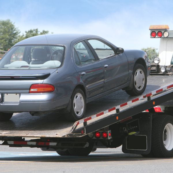 grey car being towed by a tow truck